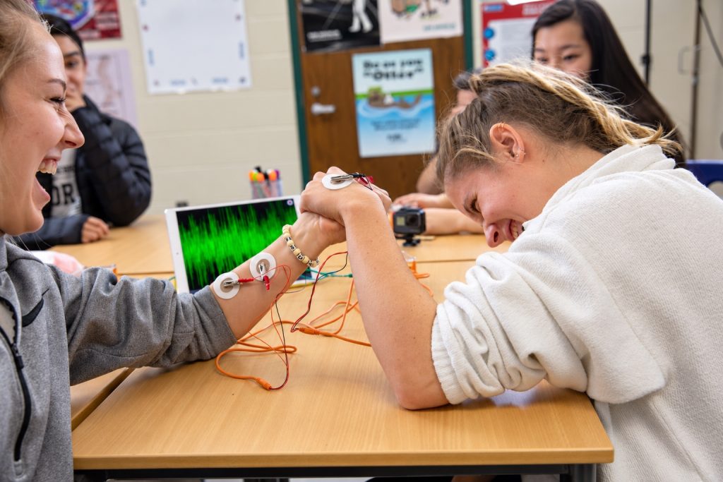 Two students arm wrestling while recording their muscle signals