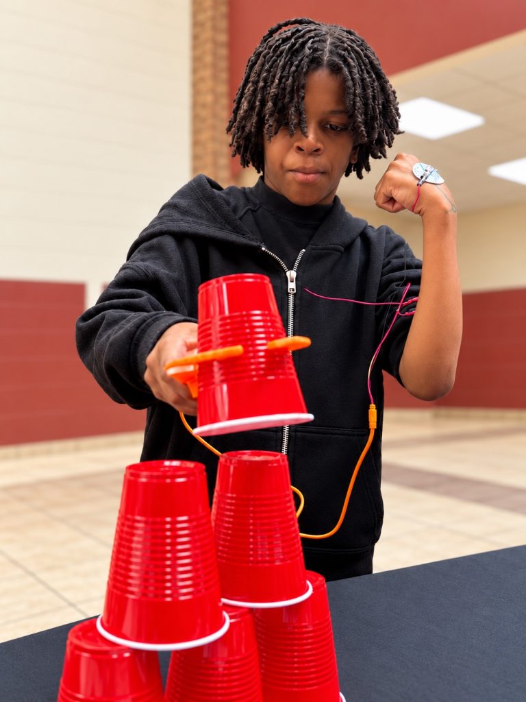 Student using a muscle signal to control a gripper and stack cups