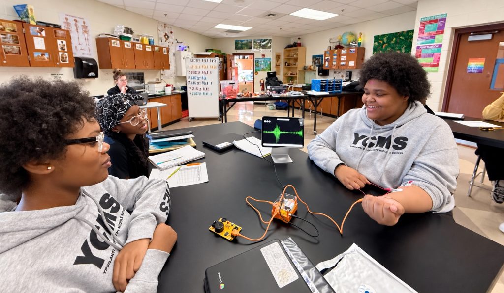 Middle school students recording arm muscle signals at a lab table